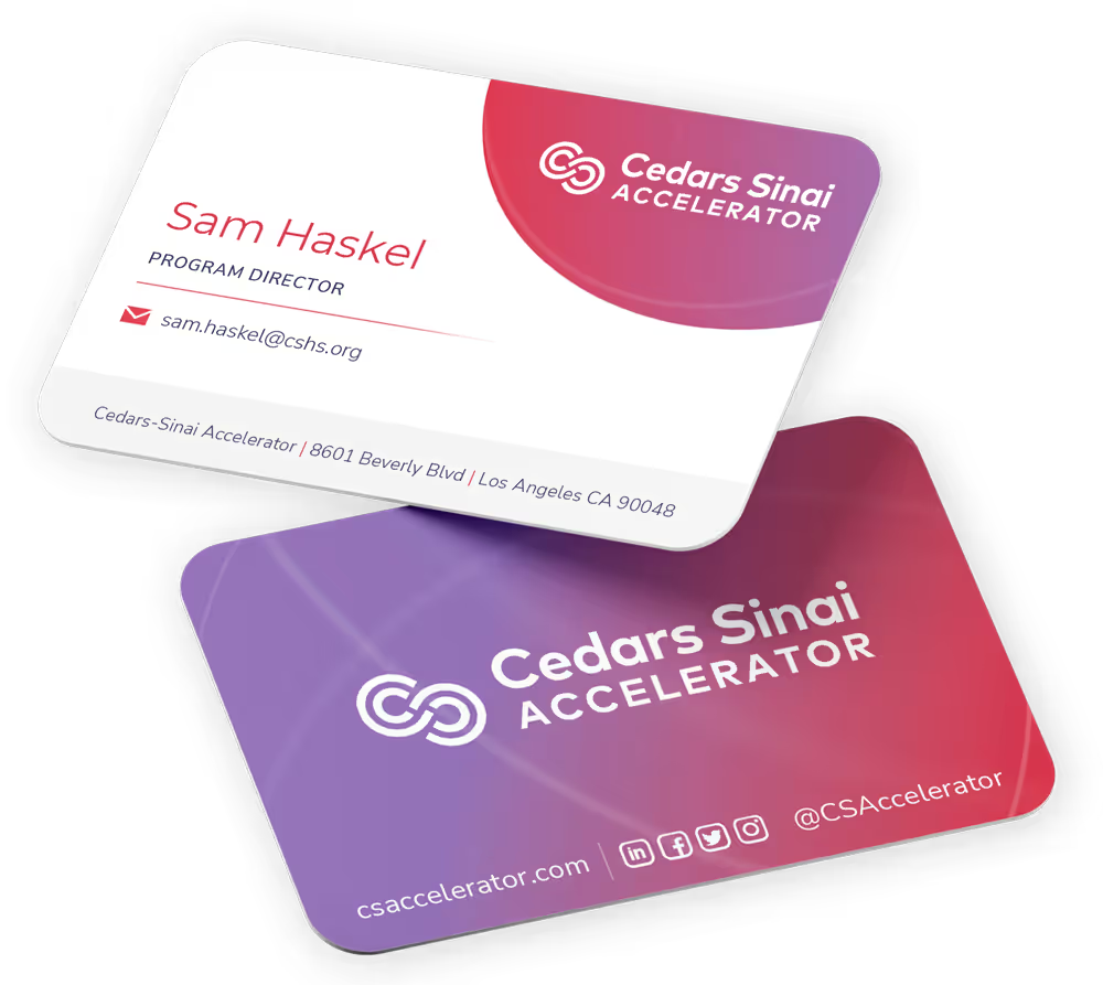 Two Cedars-Sinai Accelerator business cards, a white front with the program director's details and a pink-to-violet gradient back